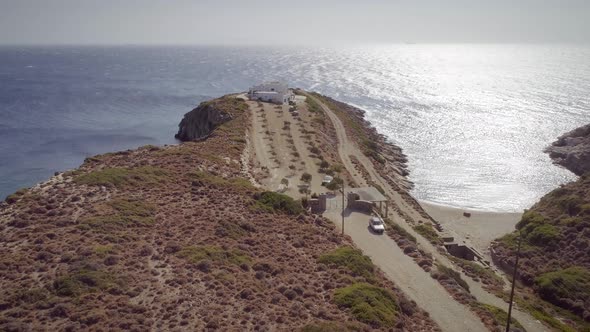 Aerial view of a dirt road with a big house at the end and the sea around.