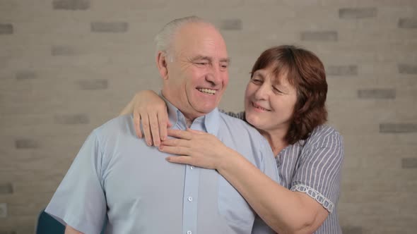 Cheerful Senior Adult Family Couple Hugging Laughing Looking at Camera