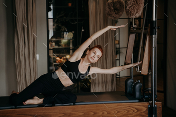 Young female pilates instructor exercising and stretching on cadillac reformer / Photodune, Misc