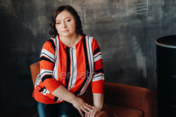 portrait of a business woman in a striped jacket sitting on a sofa in the interior / Photodune, Misc