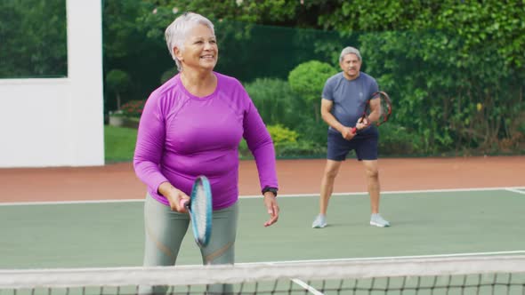 Video of happy biracial senior couple during training on tennis court