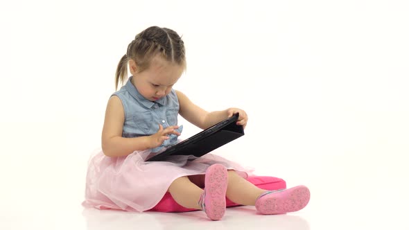 Baby Is Holding a Computer in Her Hands and Cliches, She Is in a Good Mood. White Background