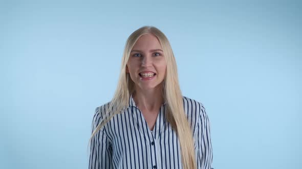 Excited Blonde Woman Yelling and Raising Fists in Cheer on Blue Background