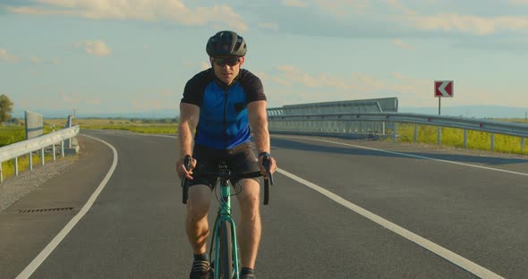 A Cyclist is Riding Along the Highway at a Slow Pace