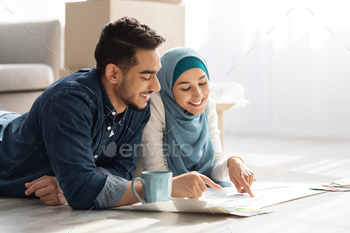 Creative muslim family laying on floor with apartment scheme / Photodune, Misc