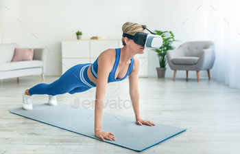 Focused woman in VR headset exercising at home / Photodune, Misc