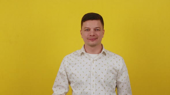 Young Handsome Guy in a Shirt Holding a Golden Bitcoin Coin on an Isolated Yellow Background