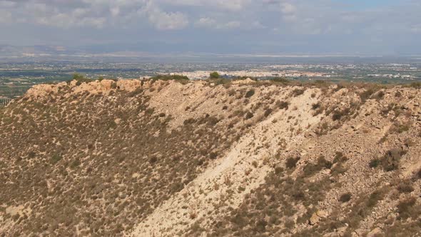 Drone Flying Over Dry Desert Hillside To Reveal Green Spanish Countryside Farm Fields.