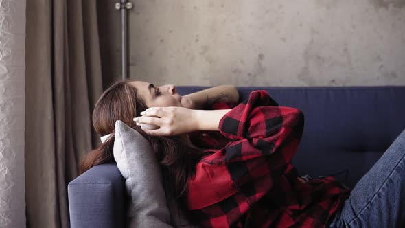 Young Attractive Girl Listening to Music While Lying on Sofa