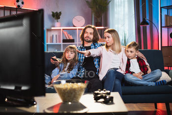 Parents with son and daughter watching TV at home / Photodune, Misc