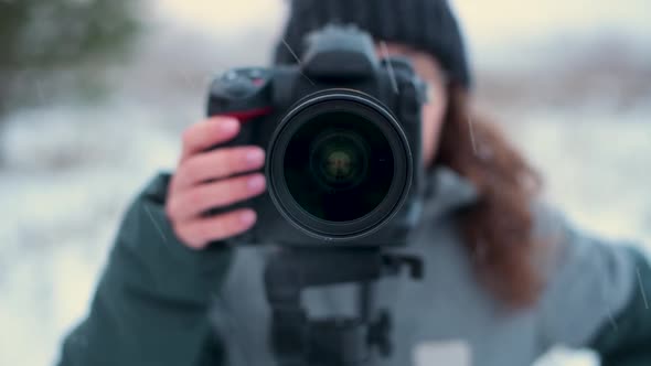 photographer takes off the lens cap of a photo camera outdoors on a snowy day