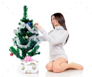 Girl poses near a Christmas tree and a gift / Photodune, Misc
