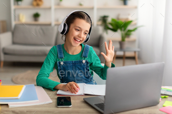 Girl sitting at table, using laptop, waving to webcam / Photodune, Misc