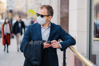 Prosperous businessman in formal wear poses at street, wears medical mask during coronavirus / Photodune, Misc