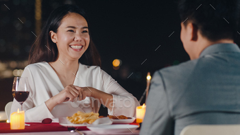 Young asian couple romantic dinner in rooftop restaurant at night city with happy moment celebrate. / Photodune, Misc