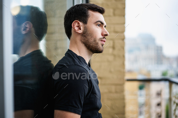  a beard in a black t-shirt on the balcony overlooking the city