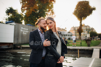 a family of two stands on a pier in Austria's old town at sunset .A man and a woman embrace on / Photodune, Misc