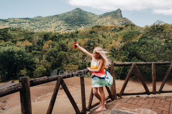 a little girl with a red can of drink in her hands against the background of the mountains of the / Photodune, Misc