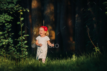 Portrait of a cute little girl runs on a green lawn in a forest. A happy child laughs and smiles / Photodune, Misc