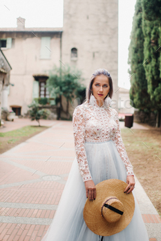 a girl with a hat in a white dress stands in the old town of Sirmione.Italy / Photodune, Misc