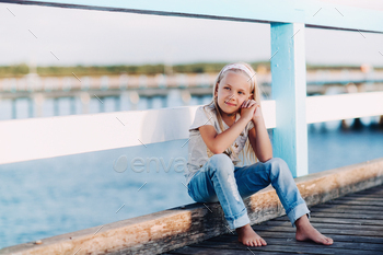 Portrait of a happy little girl sitting on a wooden bridge with sunlight / Photodune, Misc
