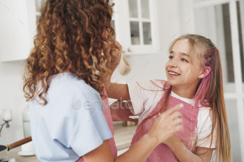 Mother and daughter having fun while cooking dough in kitchen / Photodune, Misc