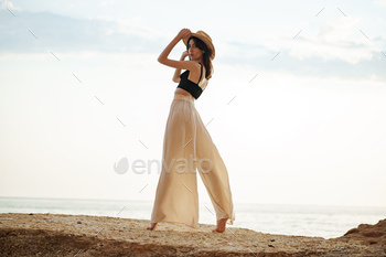 Young stylish woman standing on cliff at the sea at sunset / Photodune, Misc
