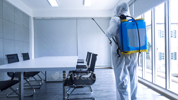 Worker in personal protective equipment (ppe) suit cleaning in building with spray / Photodune, Misc