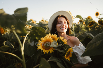 日没のひまわり畑に立っている帽子をかぶって笑顔の女性 / Photodune, Misc