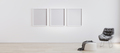 three blank poster frames in room with white wall and wooden floor with white pouf - PhotoDune Item for Sale
