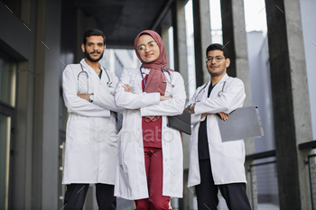Three young confident Saudi Arab doctors, standing outside the hospital and looking at camera / Photodune, Misc
