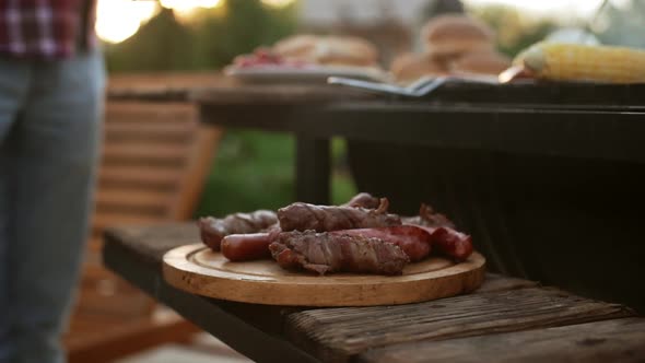 Wooden Plate with Fried Meat and Sausages Near Barbecue Grill