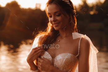 An elegant bride in a white dress enjoys nature at sunset.Model in a wedding dress in nature in the / Photodune, Misc