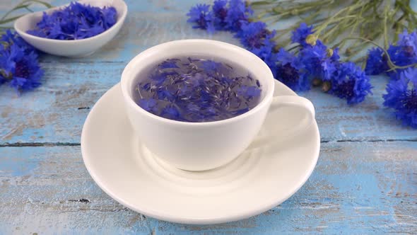 Brewing a tisanes from knapweeds flowers in white cup.