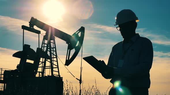 Oil Worker with a Tablet Near Crude Oil Pump