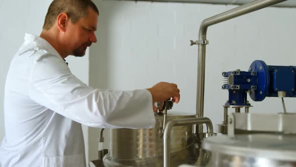 Male worker checking distillation tank in factory