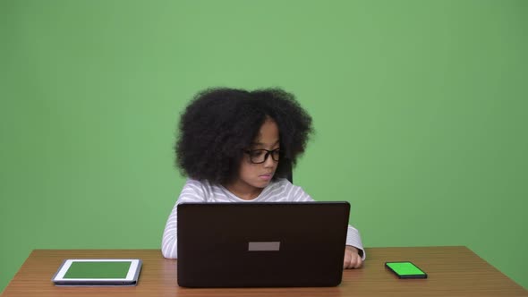 Young Cute African Girl with Afro Hair Using Laptop