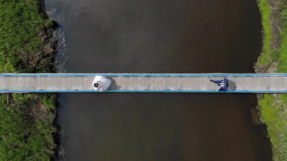 Aerial View on Top The Bride and Groom Go To Meet Each Other on the Bridge Over the River. The View