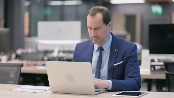 Businessman Having Back Pain While Using Laptop in Office