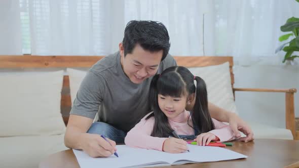 Asian loving parent father with small little kid daughter having fun drawing and coloring picture