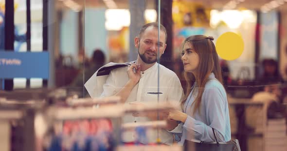 Man and Woman are Standing in a Shopping Center Behind a Shop Window Near the Store and Discussing