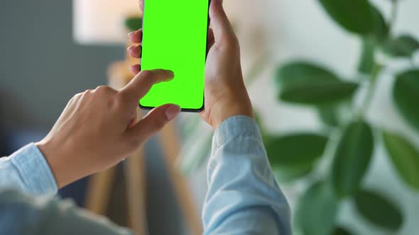 Woman at Home Using Smartphone with Green Mockup Screen in Vertical Mode