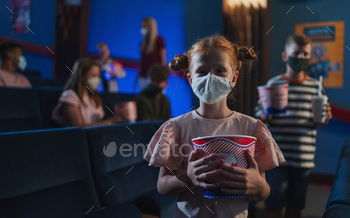 Happy small child with popcorn standing and looking at camera in the cinema, coronavirus concept / Photodune, Misc