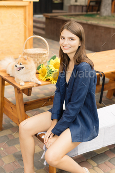 Young woman in a cotton blue clothes sitting on terrace. Wicker basket and sunflower / Photodune, Misc