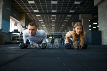 Couple doing push-ups with dumbbells in gym / Photodune, Misc