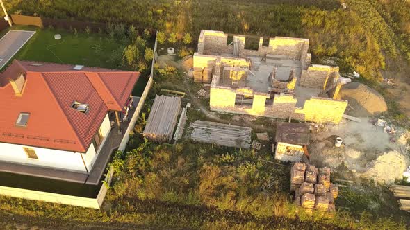 Top down aerial view of two private houses, one under construction with wooden roofing frame