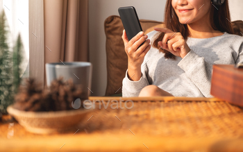自宅で携帯電話を持って使用している美しい若いアジアの女性のクローズアップ画像 / Photodune, Misc