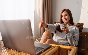 自宅でビデオ通話にラップトップコンピューターを使用しながら親指を立てる女性のサイン / Photodune, Misc