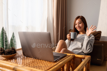 自宅で座ってコーヒーを飲みながらビデオ通話にラップトップコンピューターを使用している女性 / Photodune, Misc