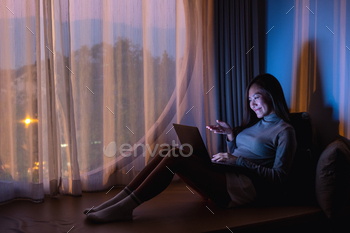自宅で深夜に明るい光の画面でビデオ通話にラップトップコンピューターを使用している女性 / Photodune, Misc